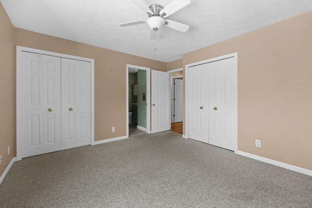 unfurnished bedroom with carpet, two closets, connected bathroom, a textured ceiling, and baseboards