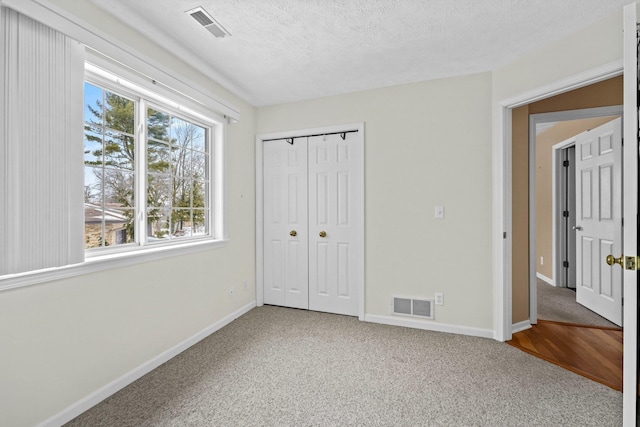 unfurnished bedroom with baseboards, carpet, visible vents, and a textured ceiling