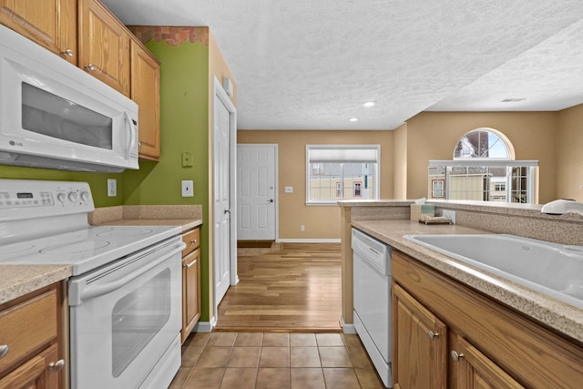 kitchen with white appliances, light tile patterned flooring, a sink, and a textured ceiling