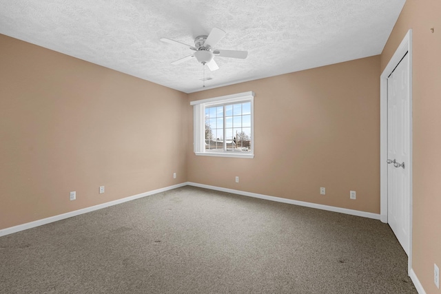 carpeted spare room with a textured ceiling, baseboards, and a ceiling fan