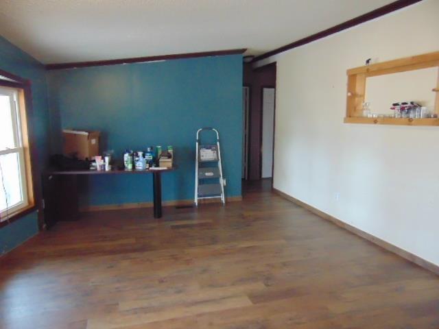 interior space with baseboards, wood finished floors, and crown molding