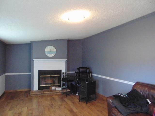 interior space featuring a textured ceiling, wood finished floors, and a glass covered fireplace