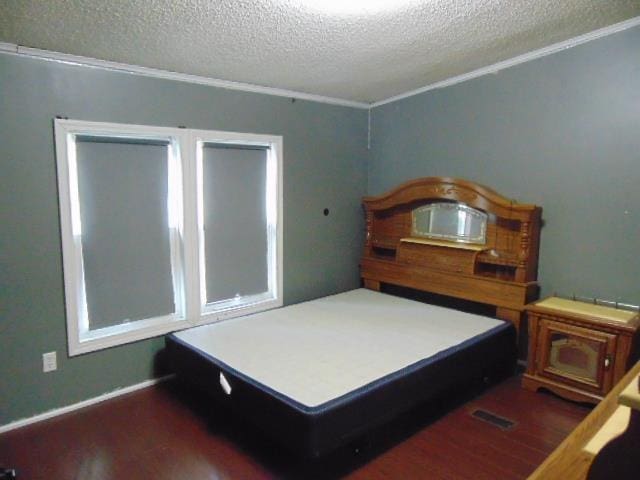 bedroom with dark wood-style floors, ornamental molding, and a textured ceiling