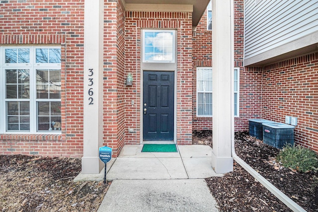 view of exterior entry with cooling unit and brick siding