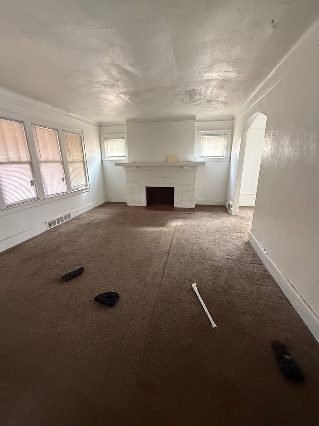 unfurnished living room with light carpet, a wealth of natural light, a textured ceiling, and visible vents