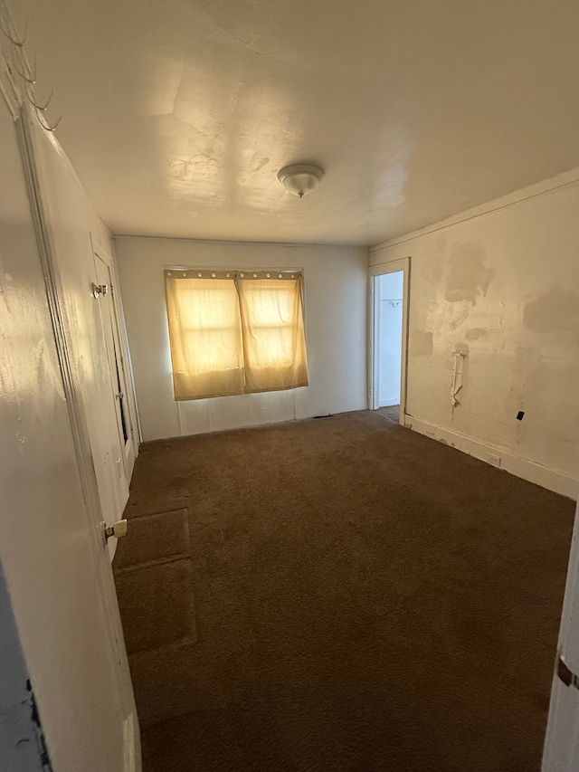 spare room with dark colored carpet