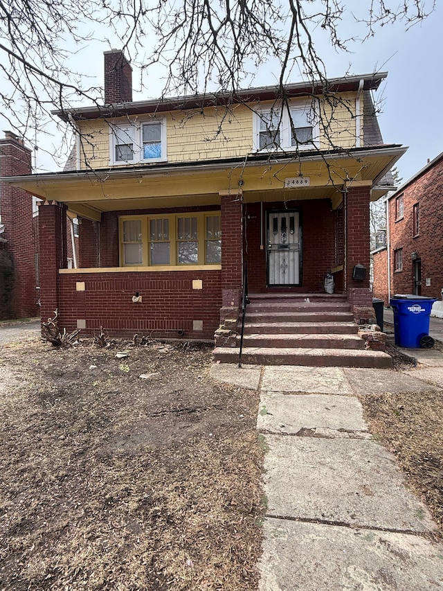 view of front facade featuring a porch, crawl space, a chimney, and brick siding