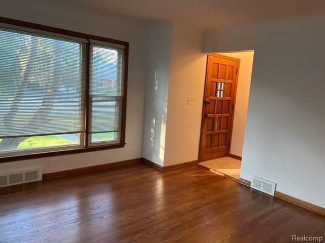 spare room featuring baseboards, visible vents, and wood finished floors