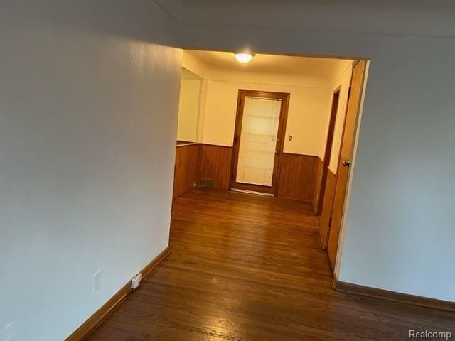 hallway featuring a wainscoted wall, wood finished floors, and wood walls