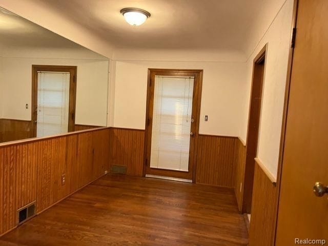 spare room featuring a wainscoted wall, wood walls, wood finished floors, and visible vents