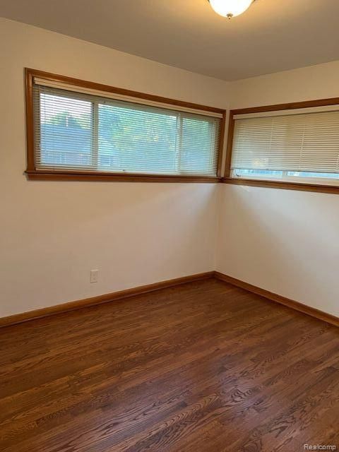 empty room with dark wood-style floors and baseboards