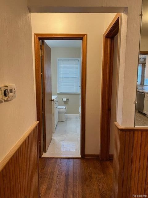 corridor with wood finished floors and wainscoting