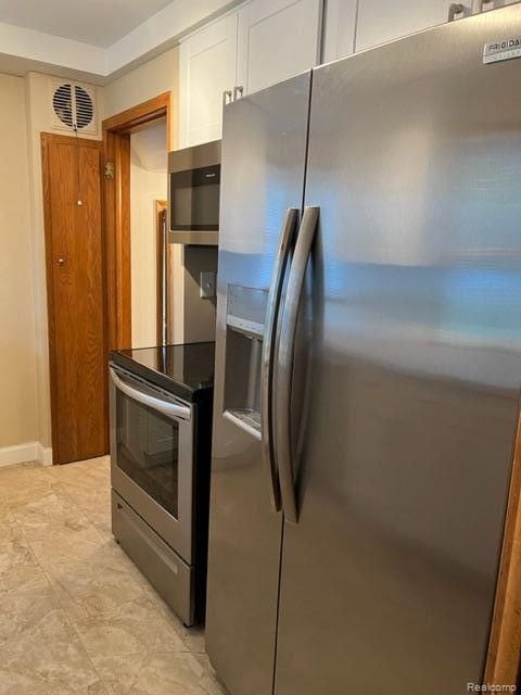 kitchen featuring appliances with stainless steel finishes, white cabinetry, and baseboards