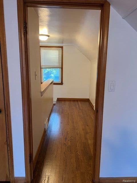 additional living space with baseboards, vaulted ceiling, and wood finished floors