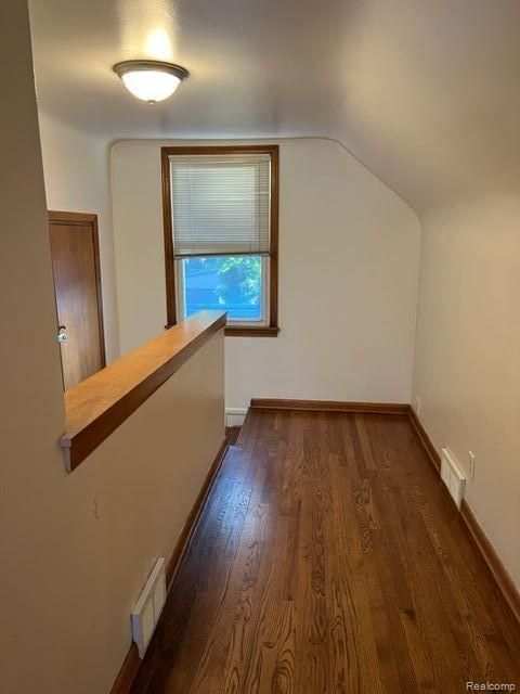 bonus room with baseboards, vaulted ceiling, visible vents, and dark wood finished floors