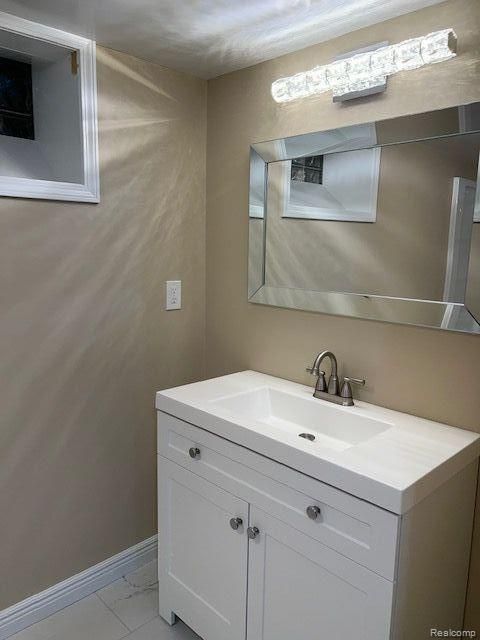 bathroom with marble finish floor, vanity, and baseboards