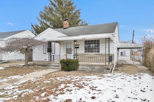 bungalow with covered porch, a chimney, an attached carport, and roof with shingles