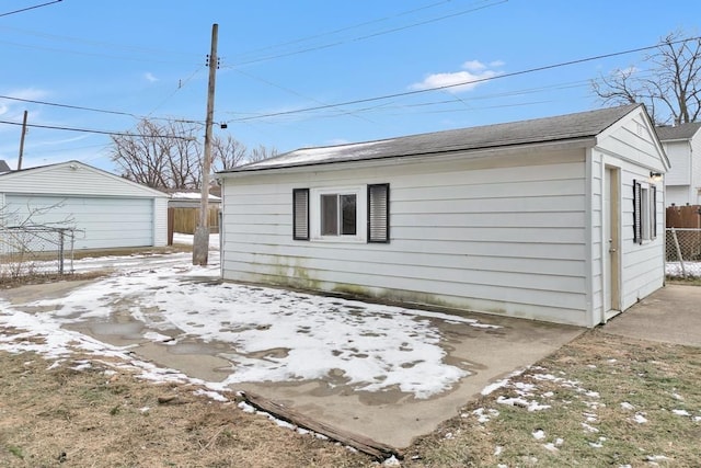 view of property exterior featuring a garage, fence, and an outdoor structure