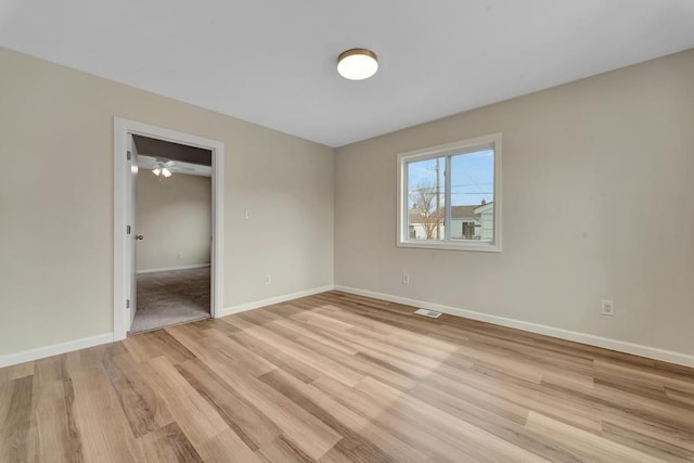 spare room featuring light wood finished floors, baseboards, and visible vents