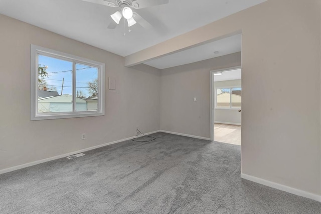 carpeted empty room featuring a ceiling fan, beam ceiling, visible vents, and baseboards