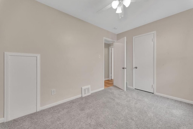 carpeted spare room with baseboards, visible vents, and ceiling fan