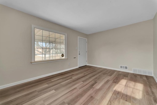 empty room featuring baseboards, visible vents, and wood finished floors