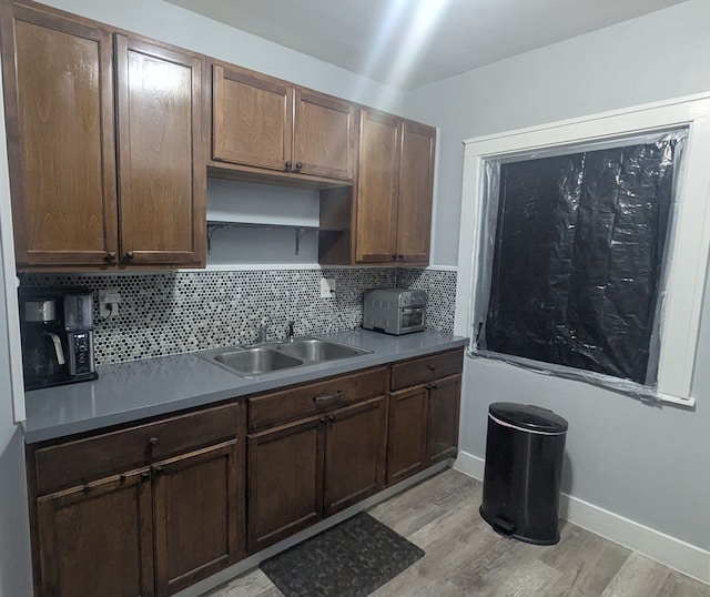 kitchen with baseboards, a sink, light wood-type flooring, open shelves, and backsplash