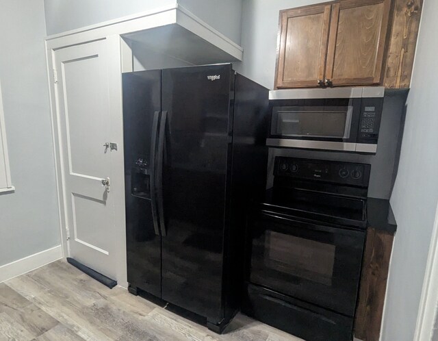 kitchen featuring black appliances, baseboards, and light wood-style floors