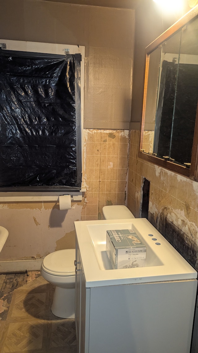 bathroom featuring vanity, toilet, and tile walls