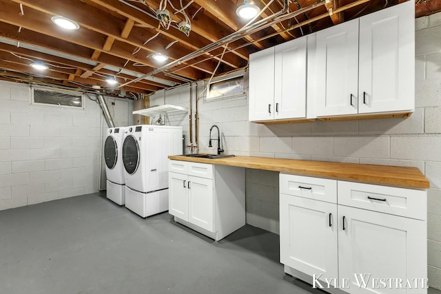 laundry area with a sink, washing machine and clothes dryer, and cabinet space