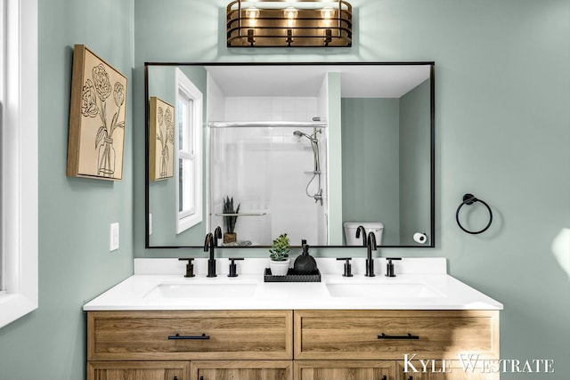 full bath with a sink, a shower stall, and double vanity