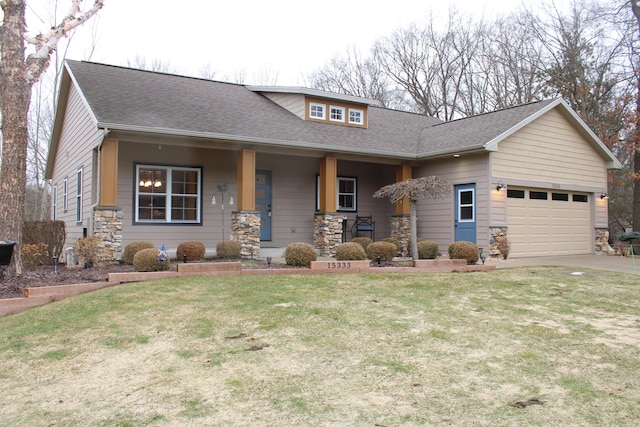 view of front facade with an attached garage, covered porch, stone siding, roof with shingles, and a front yard