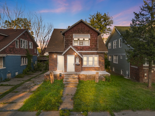 view of front facade featuring brick siding, a front lawn, and roof with shingles