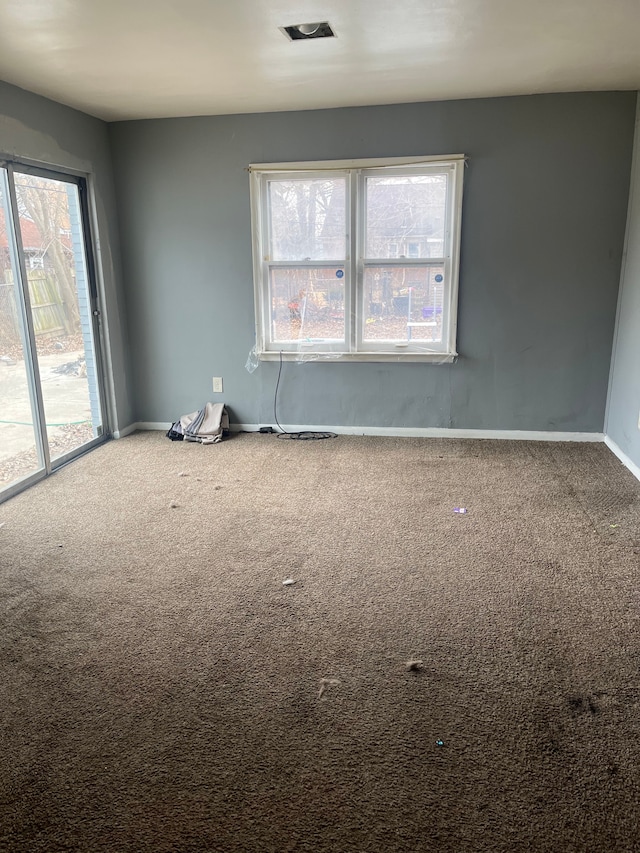 spare room with carpet flooring, visible vents, and baseboards