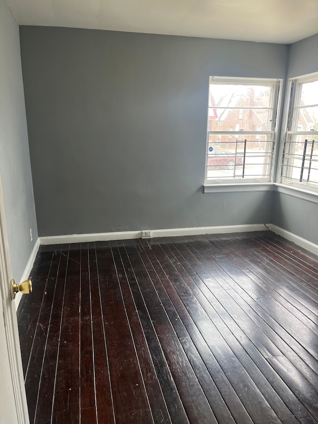 spare room featuring dark wood-type flooring and baseboards