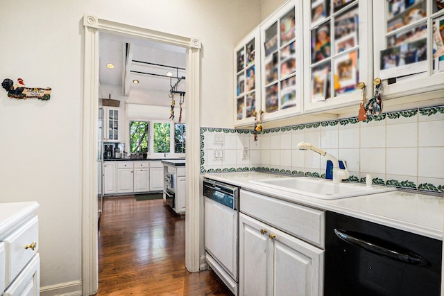 kitchen featuring dark wood-style flooring, black dishwasher, tasteful backsplash, a sink, and dishwashing machine