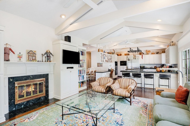 living area featuring lofted ceiling with beams, a premium fireplace, and wood finished floors