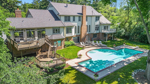 back of property featuring roof with shingles, a yard, a chimney, and a wooden deck