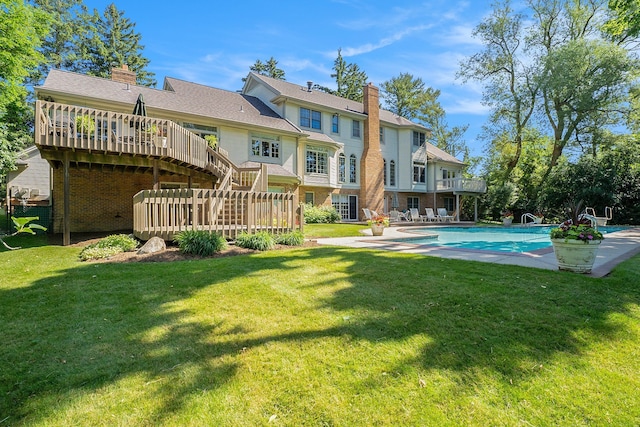 back of house with an outdoor pool, a yard, a chimney, and a wooden deck