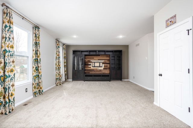 unfurnished living room with carpet, visible vents, and baseboards