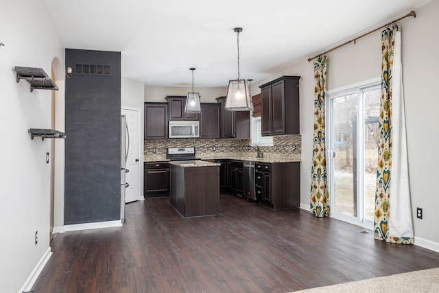 kitchen featuring plenty of natural light, backsplash, a kitchen island, appliances with stainless steel finishes, and dark brown cabinets