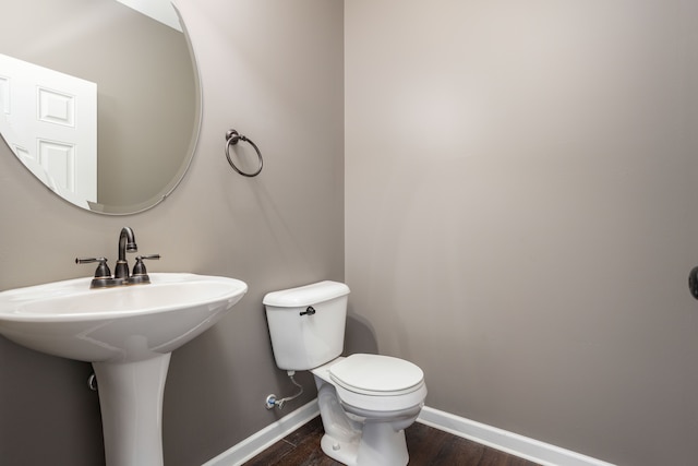 half bath featuring baseboards, toilet, and wood finished floors