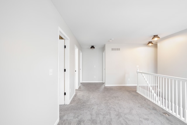 hallway featuring carpet, visible vents, and baseboards