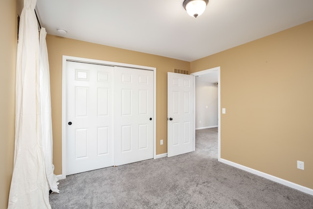 unfurnished bedroom featuring a closet, visible vents, baseboards, and carpet