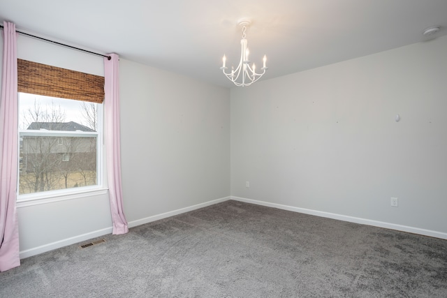 carpeted spare room with a chandelier, visible vents, and baseboards