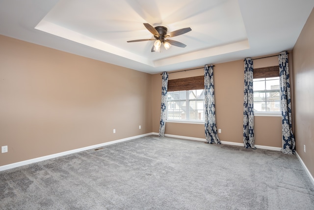 unfurnished room with a tray ceiling, baseboards, and carpet floors