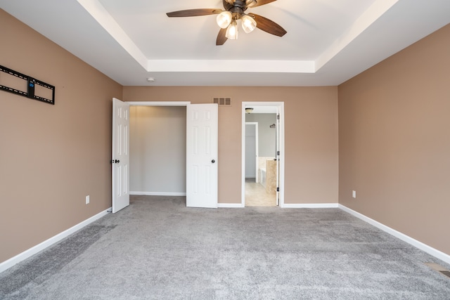 unfurnished bedroom with visible vents, a raised ceiling, and baseboards