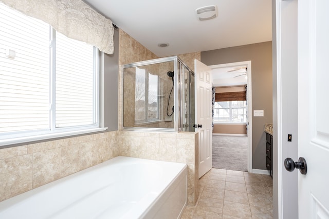 full bathroom featuring tile patterned floors, baseboards, a stall shower, a bath, and a ceiling fan