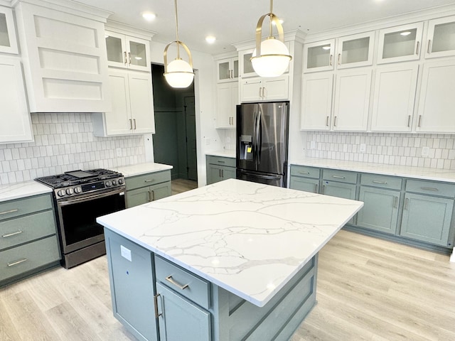 kitchen with light wood finished floors, a kitchen island, appliances with stainless steel finishes, decorative light fixtures, and exhaust hood