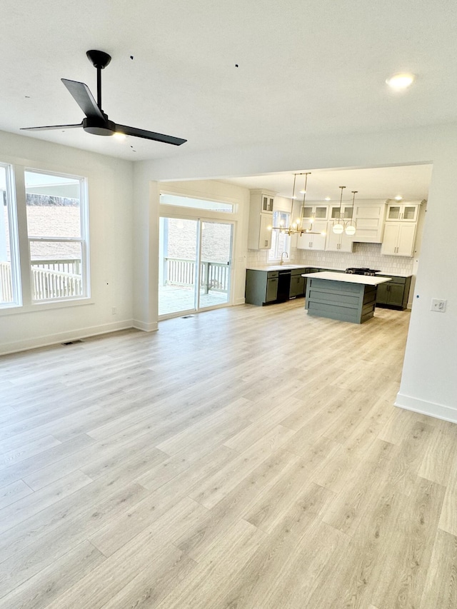 unfurnished living room featuring light wood finished floors, ceiling fan, visible vents, and baseboards